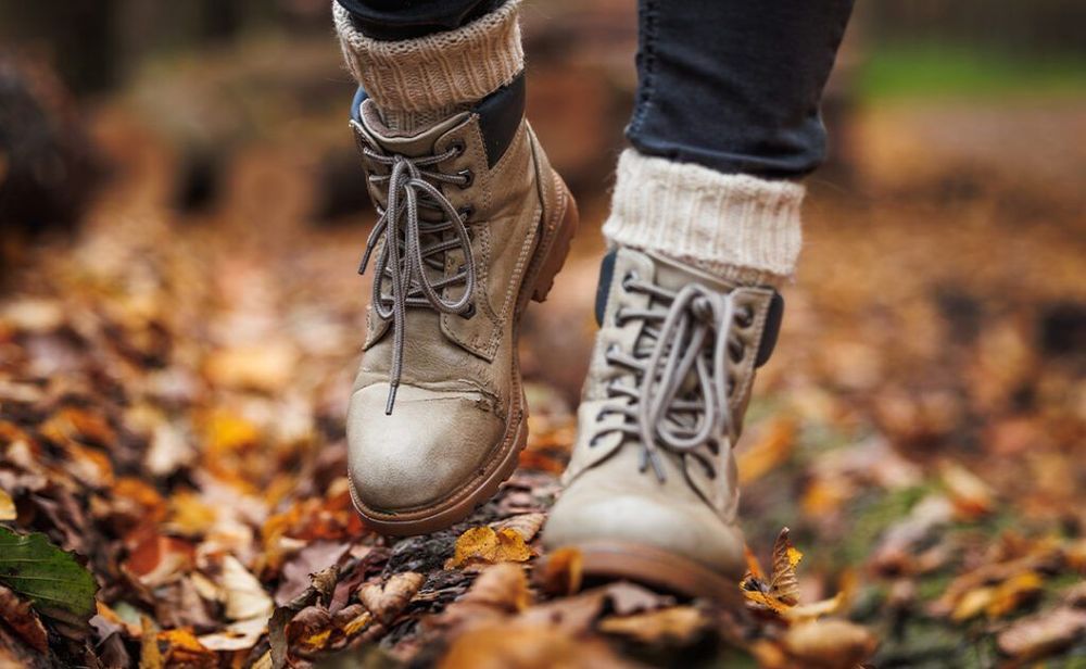Leather hiking boot with knitted socks. Walking in autumn forest